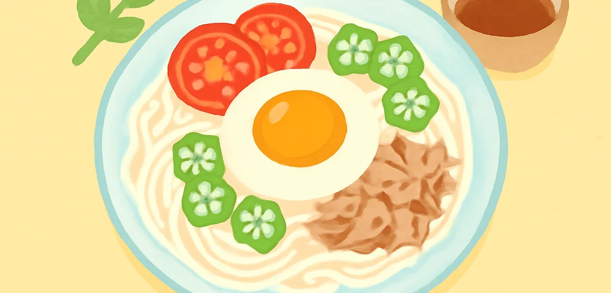 Cold somen noodles topped with poached egg, sliced okra, tomatoes, and tuna on a glass plate, refres