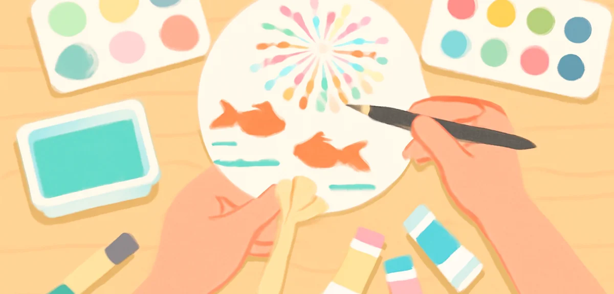 Child's hands decorating a plain white round paper fan with acrylic paints, colorful goldfish and fi